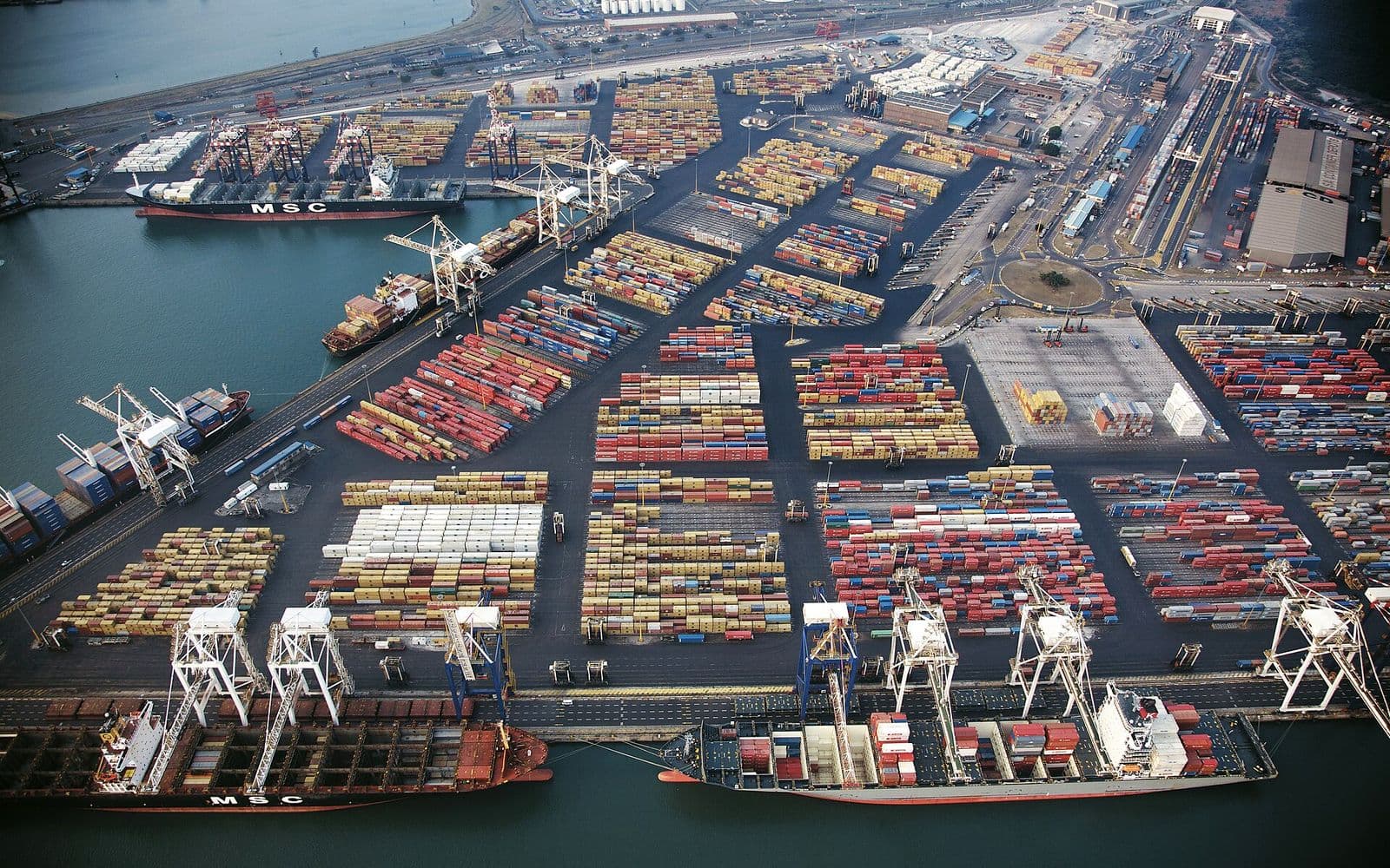 Container terminal with cranes and stacked containers.