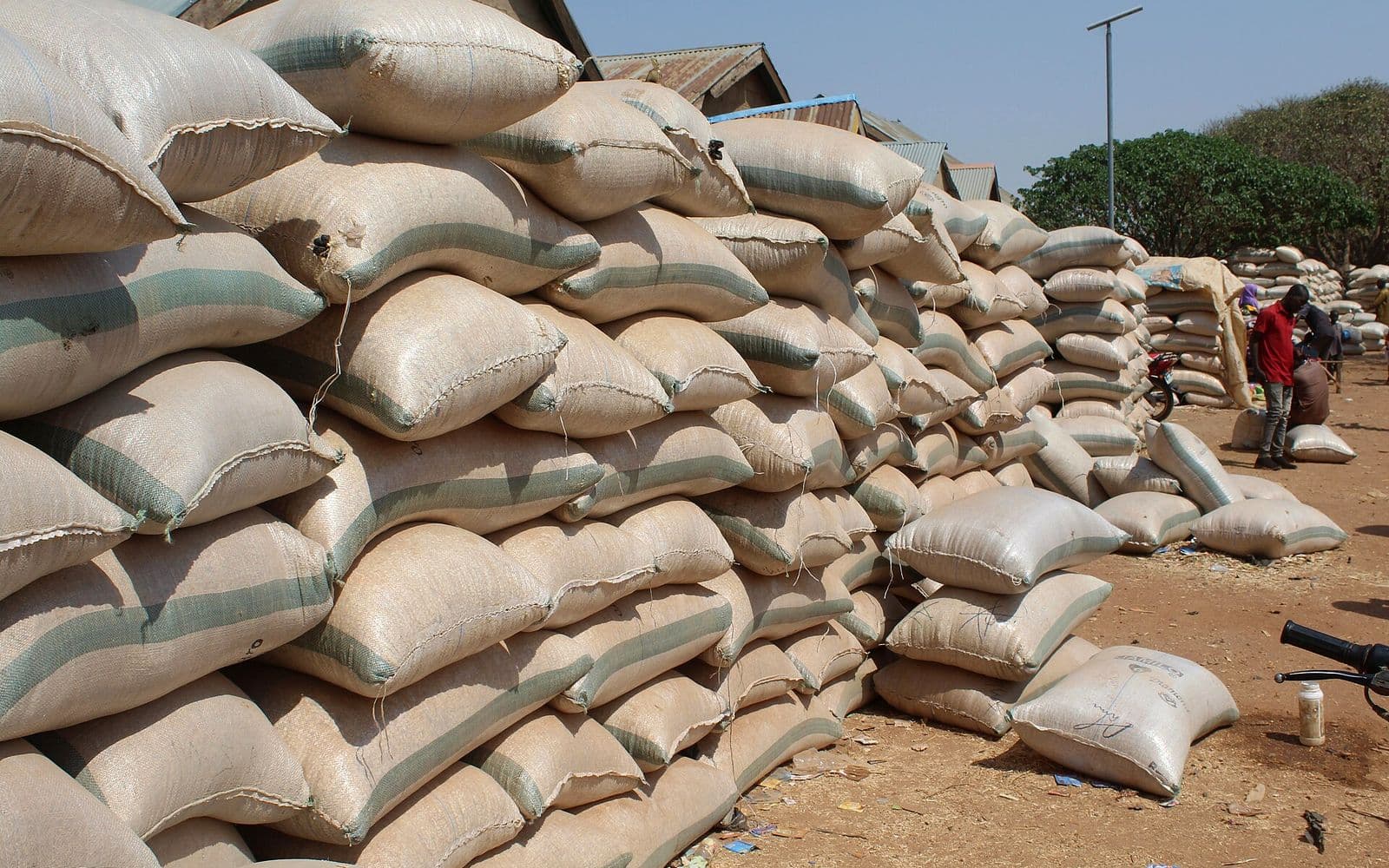 Stacked sacks of grain at a rural produce market.