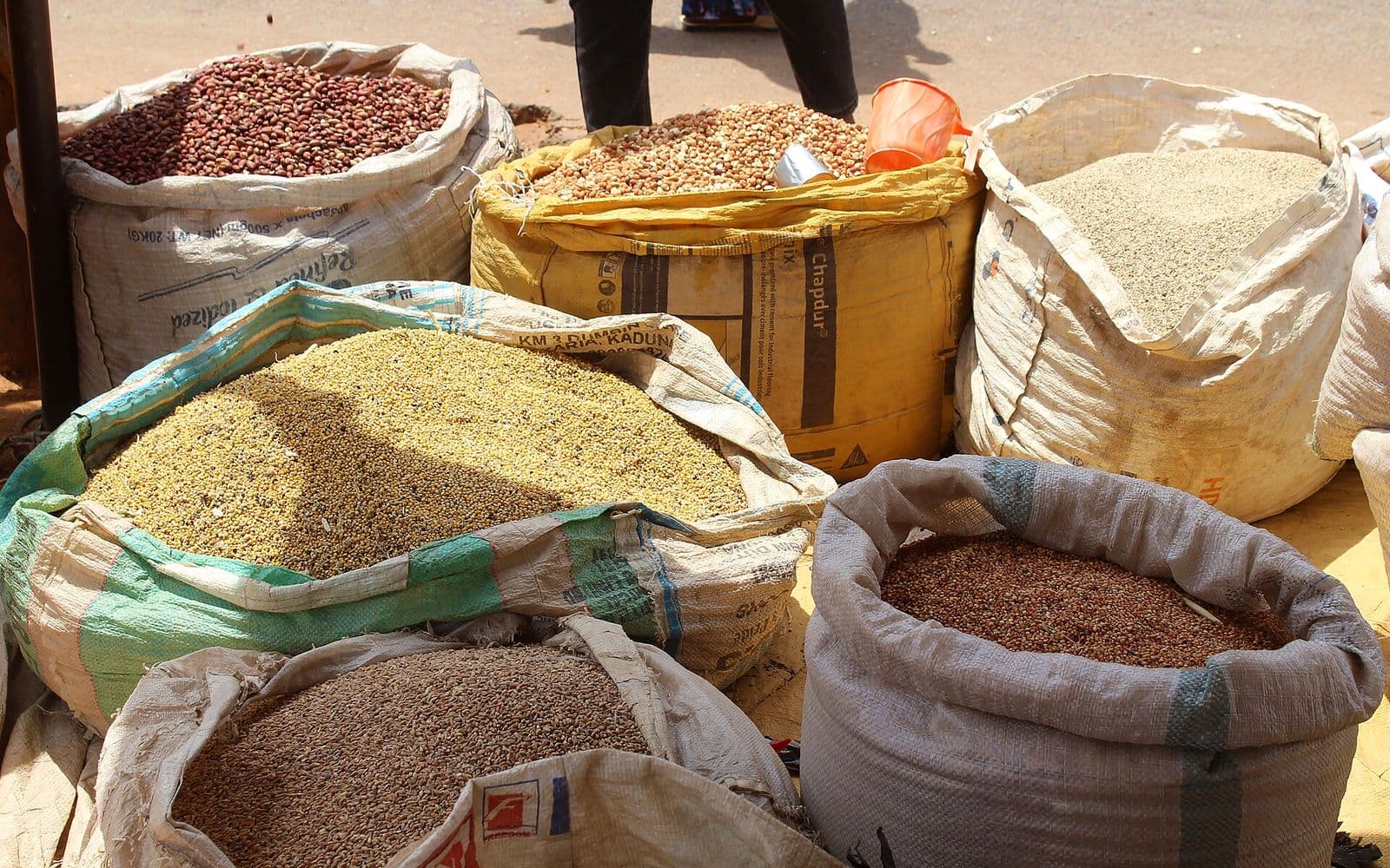 Open sacks of assorted grains and pulses offered for sale.